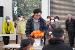 はっさく重量当てで重さを量る男性の写真