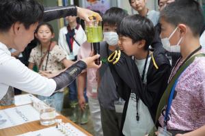 ビーカーの中の小さな生物を男の子が目を凝らしてみている写真