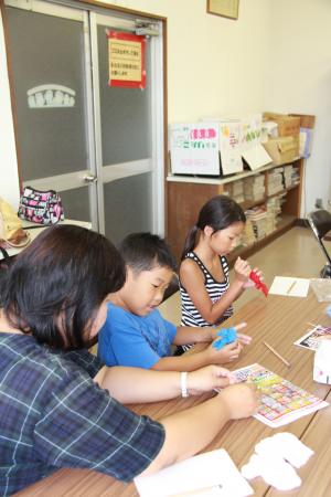 水色の金魚を作っている男の子と赤い金魚を作っている女の子の画像