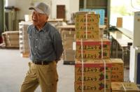 積み上げたブドウの箱の前で笑う生産者の写真